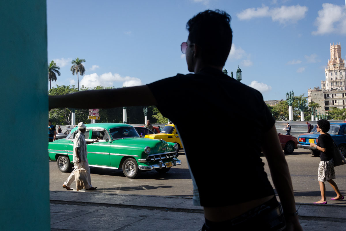 old american car through the frame of a cuban boy arm