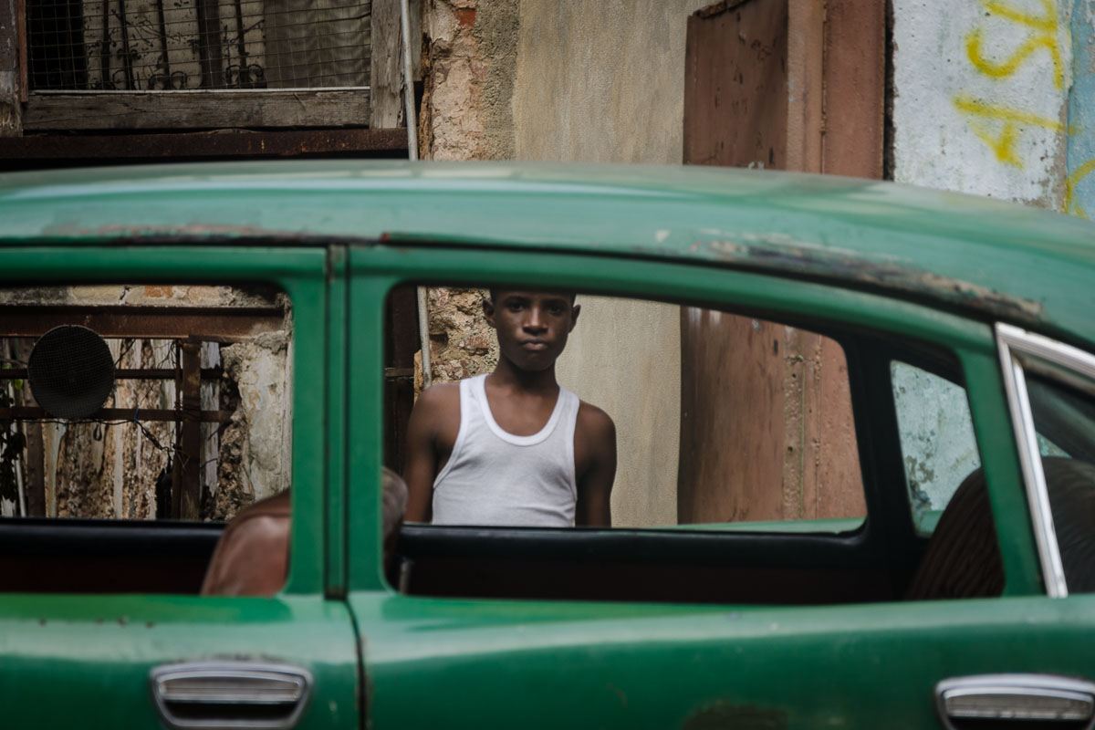 cuban boy and a green american car , practising street photography