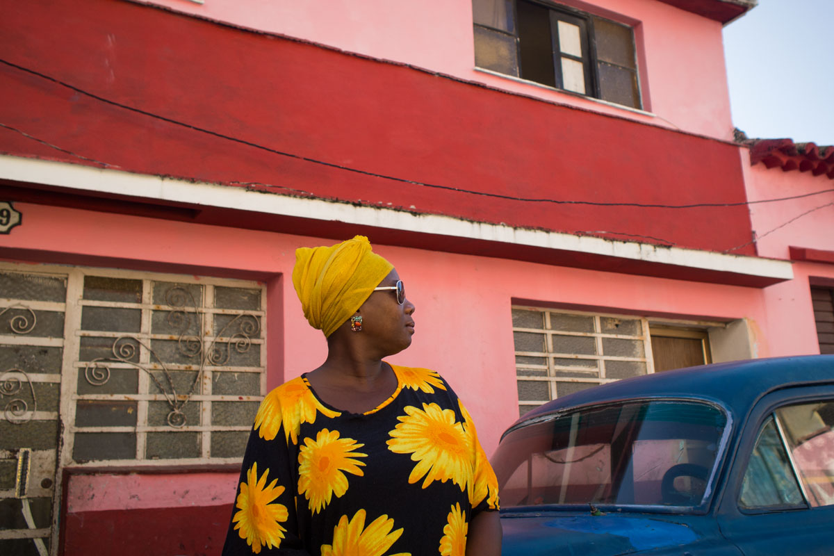 cuban woman with a blue car and multicolour background