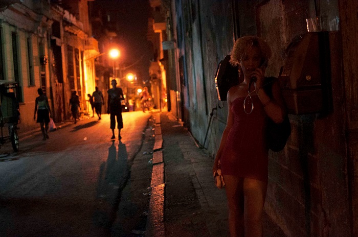 cuban woman at night calling in a public phone by louis alarcon